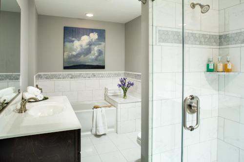 a white bathroom with a shower and a sink at The Carroll Villa Hotel in Cape May