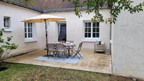 a table and chairs under an umbrella in a yard at La rocaille 3 chambres doubles in Fondettes