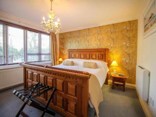 a bedroom with a large bed and a chandelier at Charismatic Cottage near St Ives (Atlantic) in Saint Erth