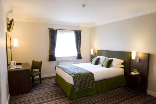 a hotel room with a bed and a window at Burntwood Court Hotel in Barnsley