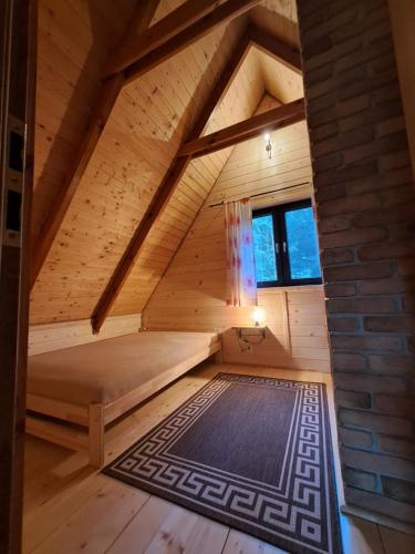 an attic room with a bed and a rug at Biały Domek in Żary