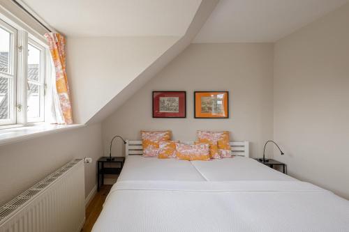 ein weißes Bett in einem Zimmer mit Fenster in der Unterkunft Aggas Hüs in Oldsum