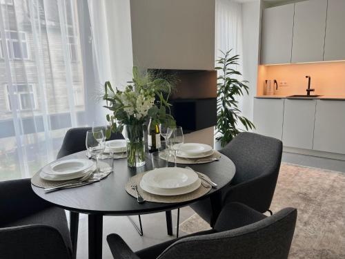 a dining room table with chairs and plates and flowers at Brand new city centre apartment, free parking spot in Tallinn