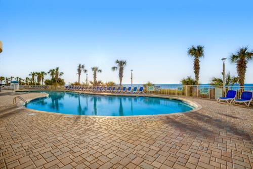 a swimming pool with blue chairs and palm trees at Bay Watch 1901 in Myrtle Beach