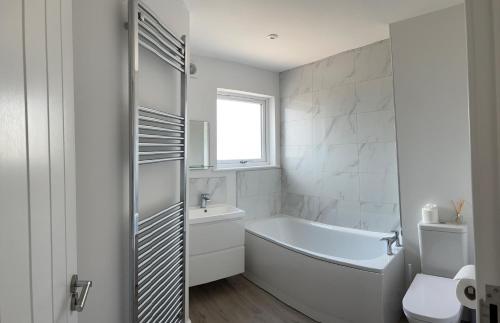 ein weißes Badezimmer mit einer Badewanne und einem Waschbecken in der Unterkunft BayVue Apartment & Apartment 7, The Bay House in Shanklin