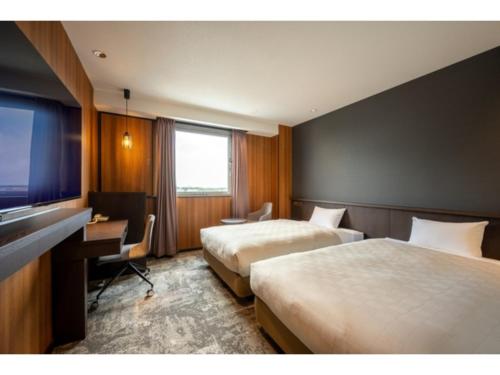 a hotel room with two beds and a desk and a television at Misawa City Hotel - Vacation STAY 81776v in Misawa