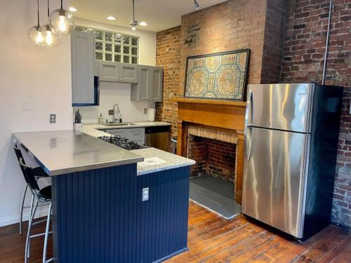 a kitchen with a stainless steel refrigerator and a brick wall at Loft in the heart of Over-The-Rhine in Cincinnati