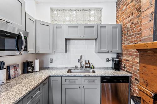 a kitchen with white cabinets and a sink and a brick wall at Loft in the heart of Over-The-Rhine in Cincinnati