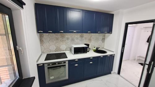 uma cozinha com armários azuis e um micro-ondas em Apartament lângă Port Turistic Mangalia 2 camere decomandate, renovat 2023 em Mangalia