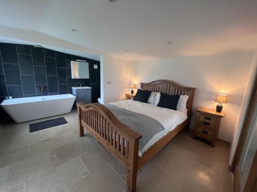 a bedroom with a large bed and a bath tub at Littlewood Cabin in Hatherleigh