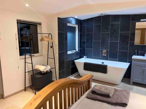 ein Badezimmer mit einer Badewanne und einem Waschbecken in der Unterkunft Littlewood Cabin in Hatherleigh