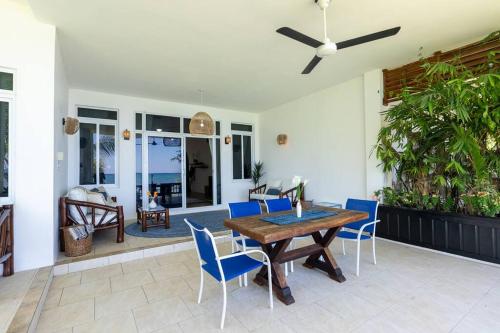 Ivy's Cove Beach Side Condo - Luxury Villa في Whitehouse: فناء مع طاولة خشبية وكراسي زرقاء