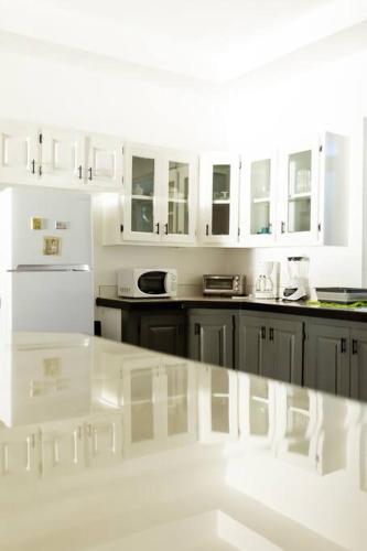 a kitchen with white cabinets and a white counter top at Ivy's Cove Beach Side Condo - Luxury Villa in Whitehouse