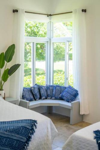 a room with a window with blue pillows on a bench at Ivy's Cove Beach Side Condo - Luxury Villa in Whitehouse