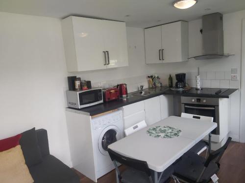 a small kitchen with a table and a white counter top at Cosy London holiday Home (Near O2 arena) in London