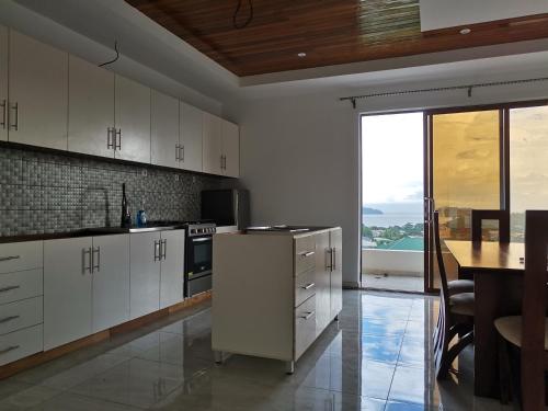 a kitchen with white cabinets and a table and a counter at FOUR IN ONE RESIDENTIAL HOMES in Limbe