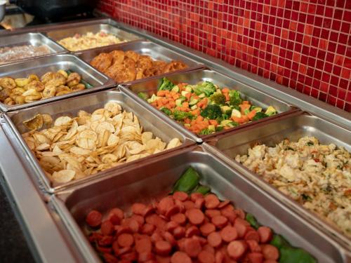 um bufê de diferentes tipos de comida em bandejas em Ramada Encore by Wyndham Guadalajara Sur em Guadalajara