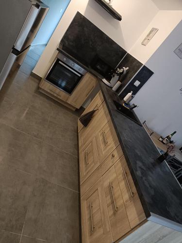 une cuisine avec des armoires en bois et un comptoir noir dans l'établissement Chez Catherine & Ludovic, à Friville-Escarbotin