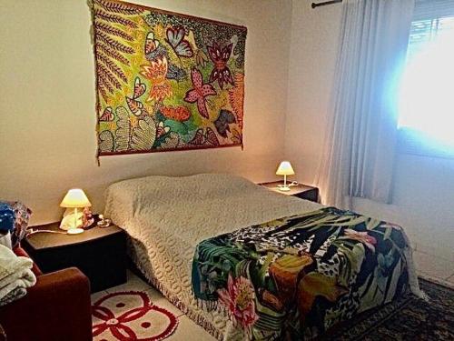 sypialnia z łóżkiem i obrazem na ścianie w obiekcie Vila agradável e confortável com piscina w mieście Pirenópolis
