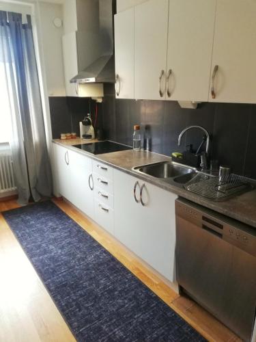 a kitchen with white cabinets and a sink and a rug at SB Studio in Malmö