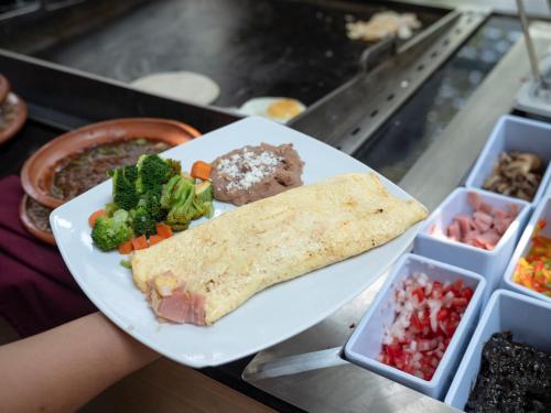 um prato com um burrito e legumes sobre uma bancada em Ramada Encore by Wyndham Guadalajara Sur em Guadalajara