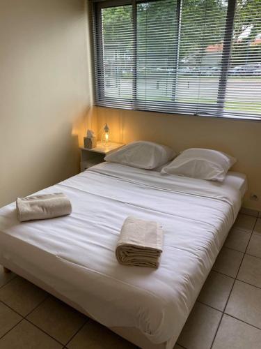 - un grand lit blanc avec 2 serviettes dans l'établissement Appartement ou studio en hyper centre, pour la plage et la rue pietonne il suffit de traverser la rue , voir la photo principale, à Andernos-les-Bains