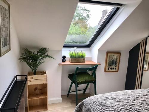 a bedroom with a window and a chair and a plant at THE MORNINGSIDE APARTMENT Charming stylish apartment in the centre of Innerleithen in Innerleithen