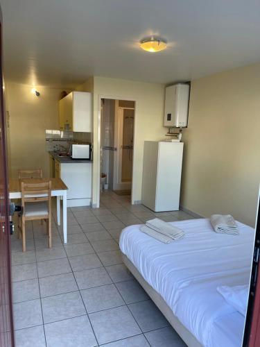 une chambre avec un lit et une cuisine avec une table dans l'établissement Appartement ou studio en hyper centre, pour la plage et la rue pietonne il suffit de traverser la rue , voir la photo principale, à Andernos-les-Bains