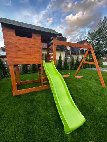 a playground with a green slide and a house at Osada Zbójnicka Turnia in Kościelisko