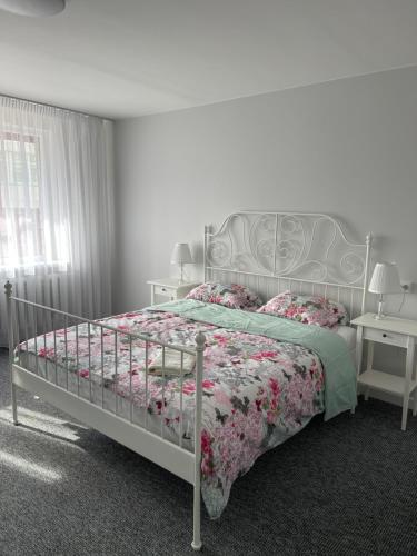 a bedroom with a bed with a floral bedspread at ROTUŠĖS g 23 APARTMENTS IN THE CITY CENTER BIRŽAI in Biržai