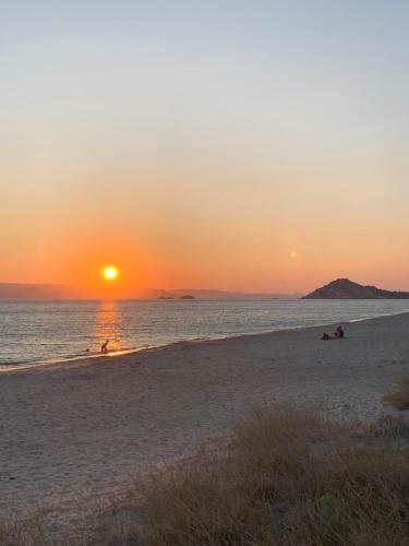 a sunset on the beach with people swimming in the water at Theoni Studios in Kastraki Naxou