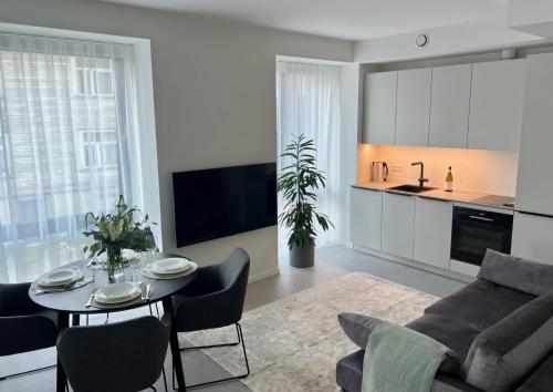 a living room with a table and chairs and a kitchen at Brand new city centre apartment, free parking spot in Tallinn