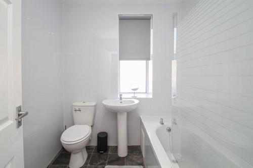 a white bathroom with a toilet and a sink at Tobago St Apartment, Greenock in Greenock