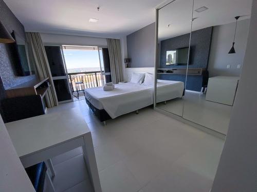 a hotel room with a bed and a balcony at Vision Acomodação Particular na Asa Norte ao Lado do SHOPPING CONJUNTO NACIONAL COM GARAGEM - 15º andar in Brasilia