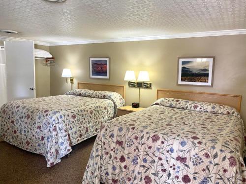 um quarto de hotel com duas camas e duas lâmpadas em Greybull Motel em Greybull