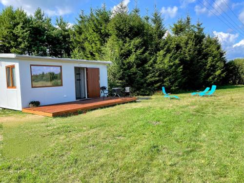 a tiny house in a field with two blue chairs at Żurawi Staw- siedlisko obok Augustowa in Augustów