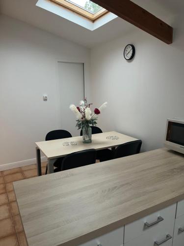 une chambre avec une table et un vase de fleurs dans l'établissement Au doux refuge, à Drouvin-les-Marais