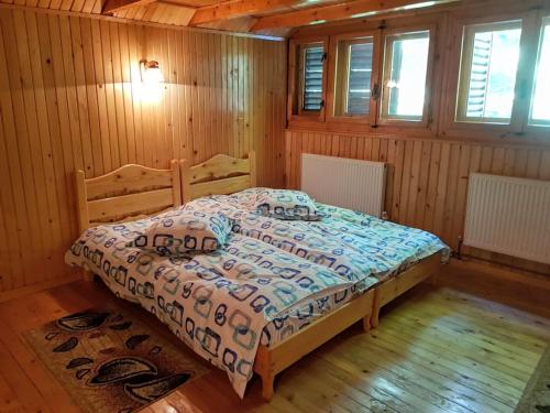 a bedroom with a bed in a wooden room at Cabana Cheia Fericirii - Forest Family Retreat in Cheia