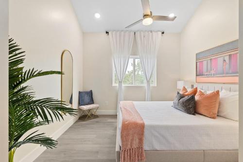 een witte slaapkamer met een bed en een plant bij Davis Shores Lookout- Dog Friendly Mins to DNTN & Beach in St. Augustine