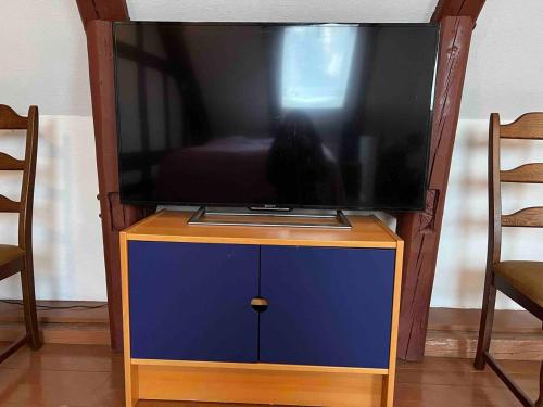 TV de pantalla plana en un soporte con armario azul en Litet gathus mitt i Ystad, en Ystad