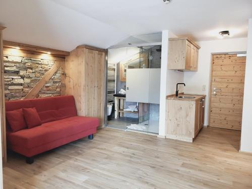 a living room with a red couch and a kitchen at Adler Hotel-Pension in Fulpmes