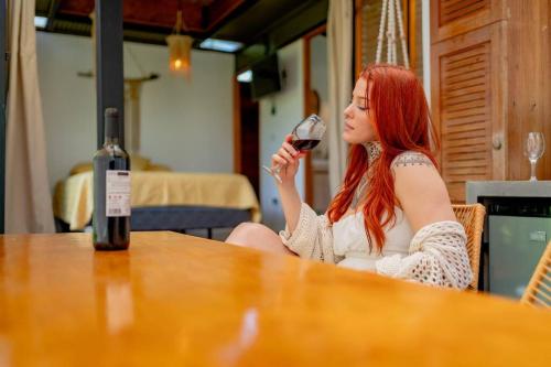 Tiny garden house في توريالبا: امرأة تجلس على طاولة تشرب كأسًا من النبيذ