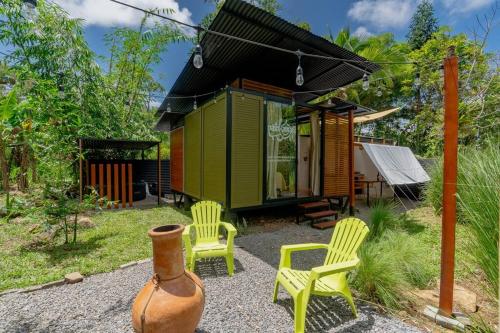 une petite maison verte avec deux chaises jaunes et un vase dans l'établissement Tiny garden house, à Turrialba