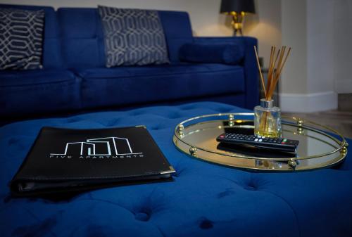 a blue couch with a table with a laptop on it at Five Apartments in Blackpool