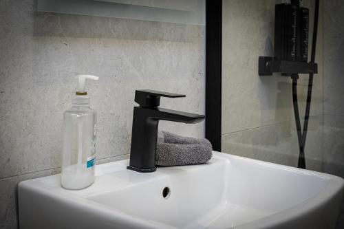 a sink with a soap dispenser and a bottle on it at Five Apartments in Blackpool