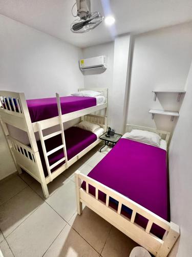 2 stapelbedden in een kamer met paarse lakens bij Hostal Lumar in Barranquilla