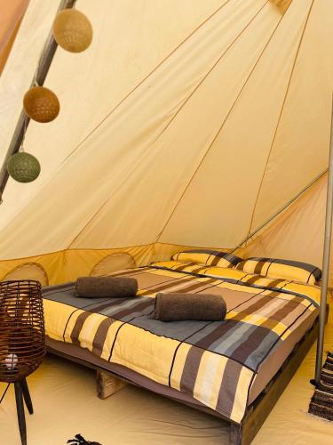 a bed in a tent with two pillows on it at WINE ROAD GLAMPING in Cuvin