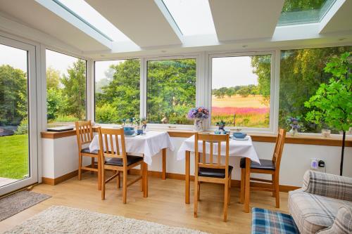 a dining room with a table and chairs and windows at Cuillich Mill Bed and Breakfast in the Highlands in Alness
