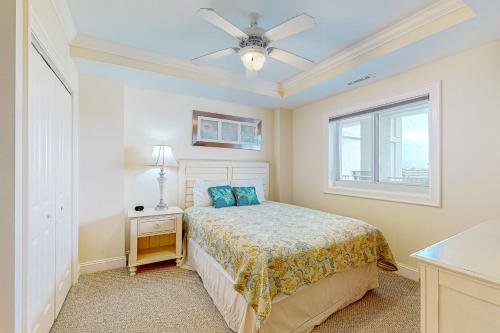 a bedroom with a bed with a ceiling fan and a window at Seventh Heaven in Indian Beach