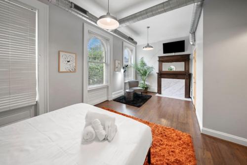 City Escape 2BR Steps to TQL near OTR and Downtown في سينسيناتي: غرفة نوم مع سرير وملاءات بيضاء وسجادة برتقالية